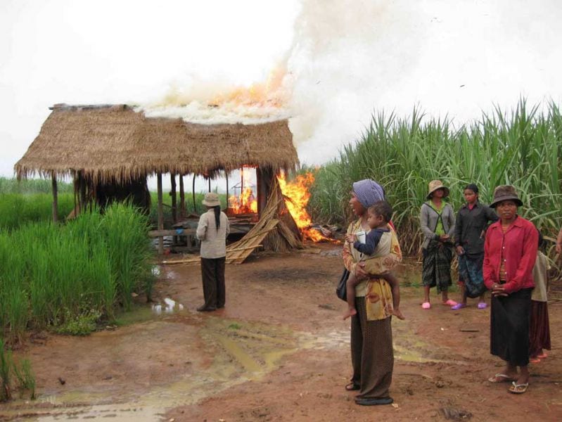 Women watch their farm houses burn during forced eviction of Bos village (October 2009)